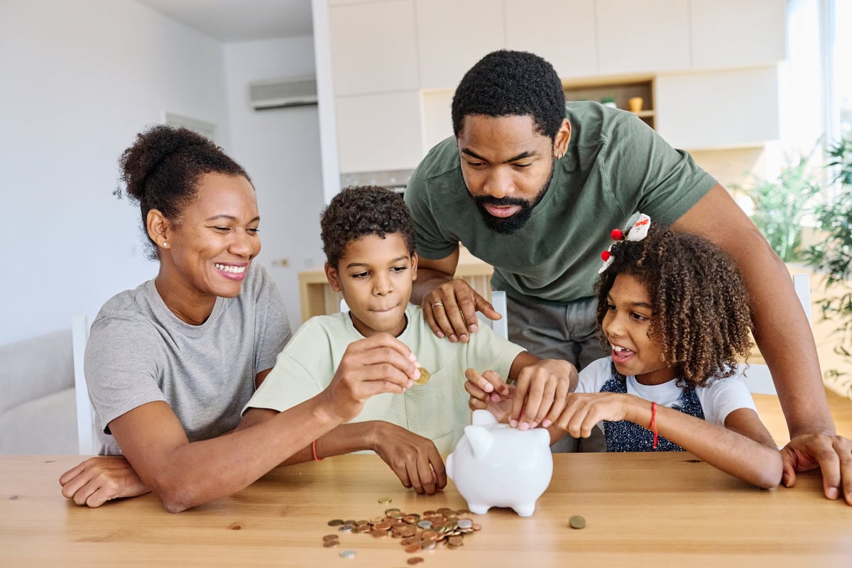 A family putting coins into a piggy bank together at home, building savings habits